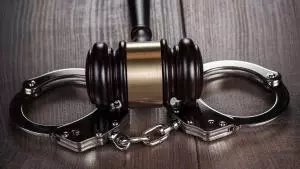 Obrazek pokazuje kajdanki i młotek sędziowski